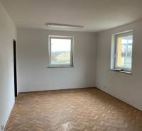 Prázdná místnost se dvěma okny a podlahou s dřevěným dekorem ve skladech a halách.