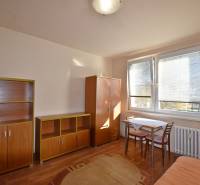 Garsonka s nábytkem, stolem a židlemi, doplněná podlahou s dřevěným dekorem.