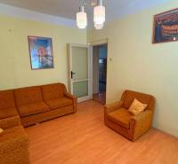 Obývací pokoj v rodinném domě s oranžovým nábytkem a podlahou s dřevěným dekorem.