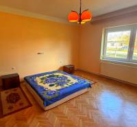 Ložnice v rodinném domě s podlahou s dřevěným dekorem a oranžovými stěnami.