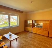 Obývací pokoj v rodinném domě s nábytkem a podlahou s dřevěným dekorem.