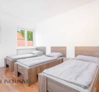 Tři postele v pokoji s podlahou s dřevěným dekorem a obrazem na stěně.