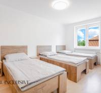 Tři postele v pokoji s podlahou s dřevěným dekorem a velkým oknem.