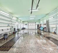 Interiérová mycí hala s mokrou podlahou a světelnými trubicemi na stropě.