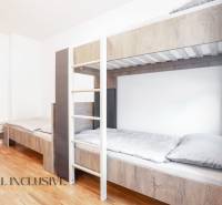 Interiér s patrovou postelí a podlahou s dřevěným dekorem v budově.