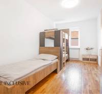 Interiér ložnice v budově s postelemi a podlahou s dřevěným dekorem.