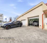 Budova v Dunajské Stredě s automobily před garážemi a dopravními značkami.