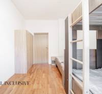 Interiér s patrovou postelí, skříně a podlaha s dřevěným dekorem.