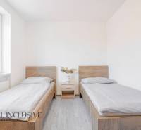 Pokoj s dvěma postelemi, nočním stolkem a podlahou s dřevěným dekorem.