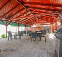 Exteriérová terasa budovy v Dunajskej Strede s dřevěnou střechou a grilem.