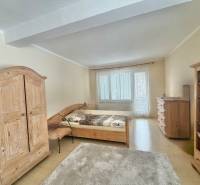 Ložnice v rodinném domě s dřevěným nábytkem a podlahou s dřevěným dekorem.