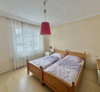 Ložnice s manželskou postelí a lustrem v rodinném domě s podlahou s dřevěným dekorem.