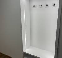 Vestavěná předsíňová skříň v 3-pokojovém bytě s háčky a podlahou s dřevěným dekorem.