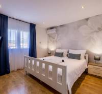 Světlá ložnice s TV, klimatizací a podlahou s dřevěným dekorem ve vile.