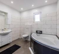 Koupelna ve vile s vanou, závěsným WC a moderními obklady.