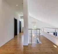 Interiér vily s bílými stěnami, podlahou s dřevěným dekorem a zábradlím.