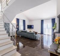 Obývací pokoj vily s lesklou podlahou a modrými závěsy.