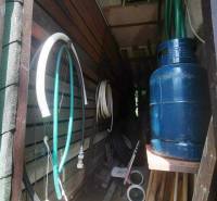 Úložný prostor u chaty s hadicemi, plynovou nádrží a různým nářadím v Košicích.