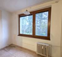 Pokoj s radiátorem, velkým oknem a dlažbou v 2pokojovém bytě.