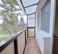 Balkon v 2-pokojovém bytě s výhledem na zeleň, podlaha s dlažbou.