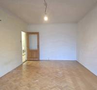 Pokoj v 2-pokojovém bytě s podlahou s dřevěným dekorem a otevřenými dveřmi.