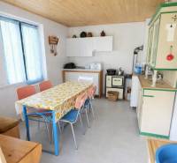 Kuchyně na chatě s barevnými židlemi a květinovým ubrusem na stole.