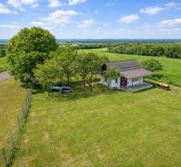 Chata v Obeckově obklopená velkou travnatou zahradou a stromy.