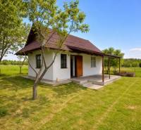 Chata v Obeckově obklopená zelenými loukami a stromy pro klidný odpočinek.