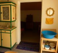 Interiér chaty s dřevěným dekorem stropu, vintage nábytkem a modrou lavórou.