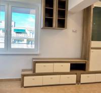 Obývací stěna v 1-pokojovém bytě s podlahou s dřevěným dekorem a výhledem z okna.