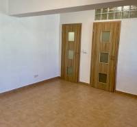 Interiér 1-pokojového bytu s keramickou podlahou a dvěma dveřmi s dřevěným dekorem.