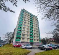 Výškový bytový dům na Třídě SNP v Banské Bystrici s parkovištěm v popředí.