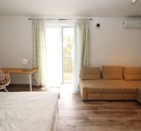 1-pokojový byt s gaučem, postelí, psacím stolem a podlahou s dřevěným dekorem.