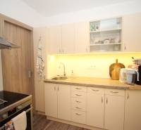 Kuchyně v 1-pokojovém bytě se světlým nábytkem a podlahou s dřevěným dekorem.