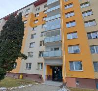 Sedmipatrový bytový dům na ulici Za dráhou v Ružomberku obklopený stromy.