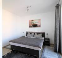 Světlá ložnice v 2pokojovém bytě s pohodlnou postelí a kobercem.