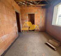 Interiér rozestavěného rodinného domu s odkrytými cihlami a stavebními materiály.