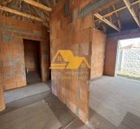 Rozestavěný rodinný dům s pohledem na stěny bez omítky a dřevěným krovem.