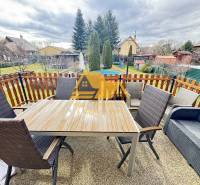 Na terase chaty v Nových Zámkoch se nachází stůl s křesly a pohovkou.