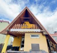 Dřevěná chata s terasou v Nových Zámcích pod modrou oblohou.