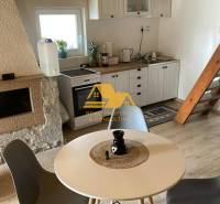 Interiér chaty se stolem, čtyřmi židlemi a kuchyňským koutem s podlahou s dřevěným dekorem.