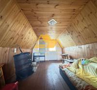 Podkroví v chatě s dřevěným dekorem a jednoduchým vybavením, příjemný prostor k odpočinku.