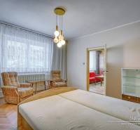 Ložnice rodinného domu se světlým dřevěným nábytkem a pohodlnými křesly.