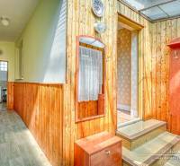 Dřevěný interiér s chodbou a vstupem v rodinném domě se světlými stěnami.