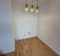 Interiér 1-pokojového bytu s podlahou s dřevěným dekorem a závěsnými svítidly.