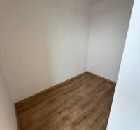 Prázdná místnost v 1-pokojovém bytě s podlahou s dřevěným dekorem, bílé stěny.