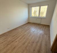 Pokoj v 2-pokojovém bytě s podlahou s dřevěným dekorem a velkým oknem.