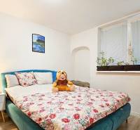 Ložnice v rodinném domě s květinovým vzorem postele a dekoracemi.