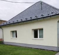 Rodinný dům v Bernolákově s trávníkem, šedou střechou a světlou fasádou.