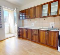 Kuchyně v 3-pokojovém bytě s linkou, spotřebiči a podlahou s dřevěným dekorem.